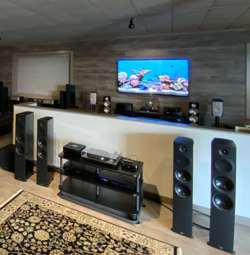 A a home theater setup, with musiplayers and multitude of speakers and a TV displaying an aquariam screen saver