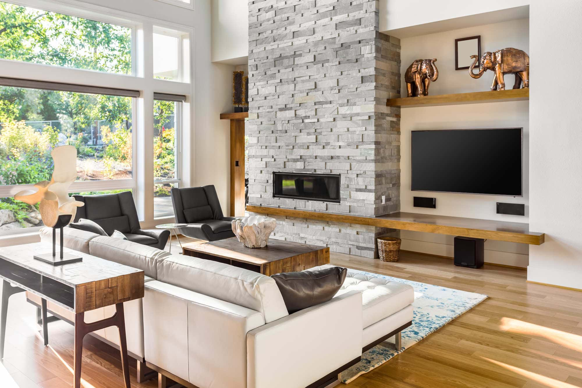 Modern living room with big screen tv, surround sound system, white leather couch, and wooden floors